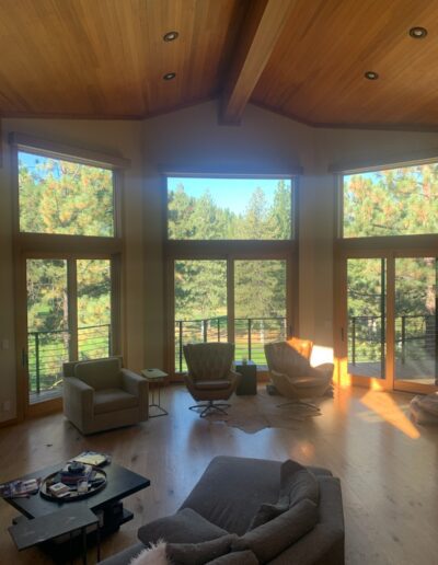 Spacious living room with large windows overlooking a forest.