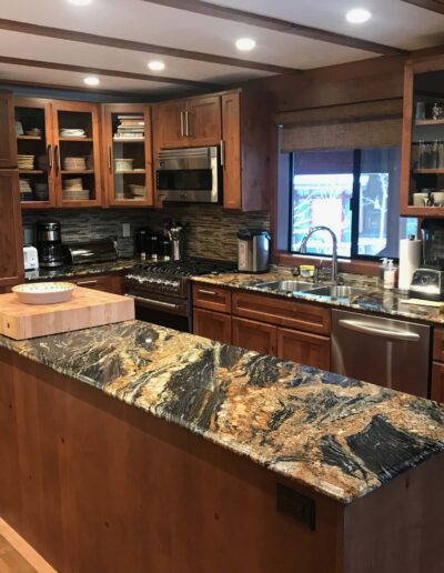 Modern kitchen interior with wooden cabinets, stainless steel appliances, and a central island with a unique stone countertop.